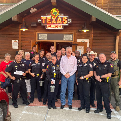 A group gathered in front of a Texas Roadhouse restaurant.