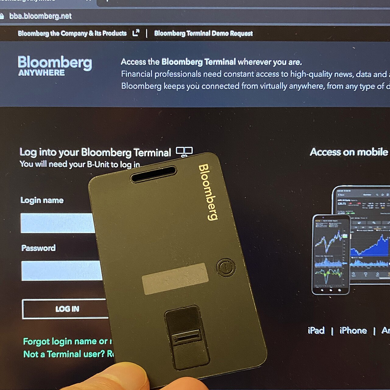 A Bloomberg B-Unit device for remote authentication displayed in front of the Bloomberg Anywhere login screen.