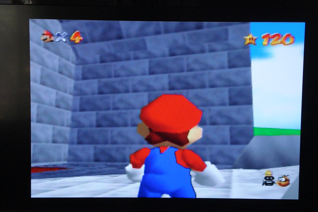 Super Mario 64 gameplay screen showing Mario facing a stone wall.