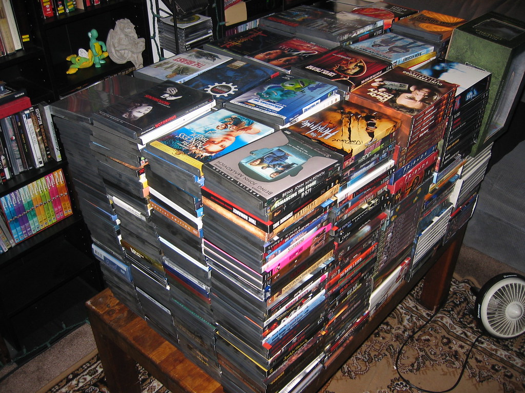 Stacks of assorted DVD cases on a table.